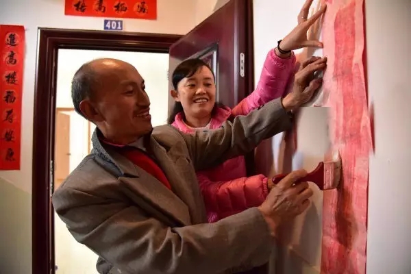 “第一书记”李雪梅与谢岩村易地扶贫搬迁户一起贴对联庆贺迁入新居。